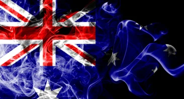 A stylized and smoky rendition of the Australian flag, with the Union Jack and Southern Cross partially obscured by blue and white smoke effects, all on a dark background.